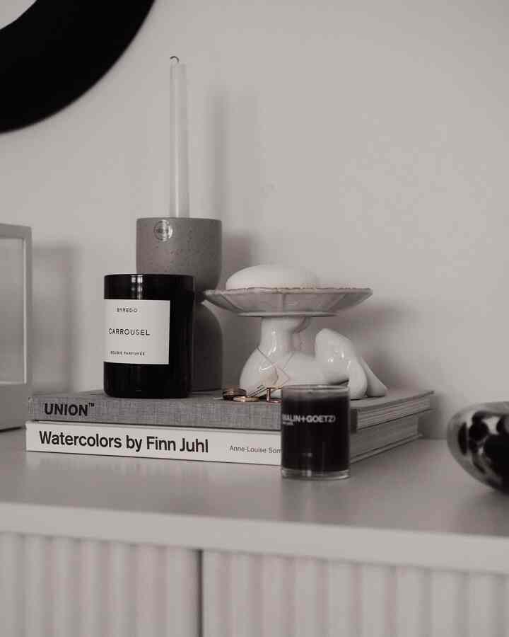 Natural beige-toned living room corner featuring minimalistic candles, tray, and interior books arranged with curated objets for a serene atmosphere