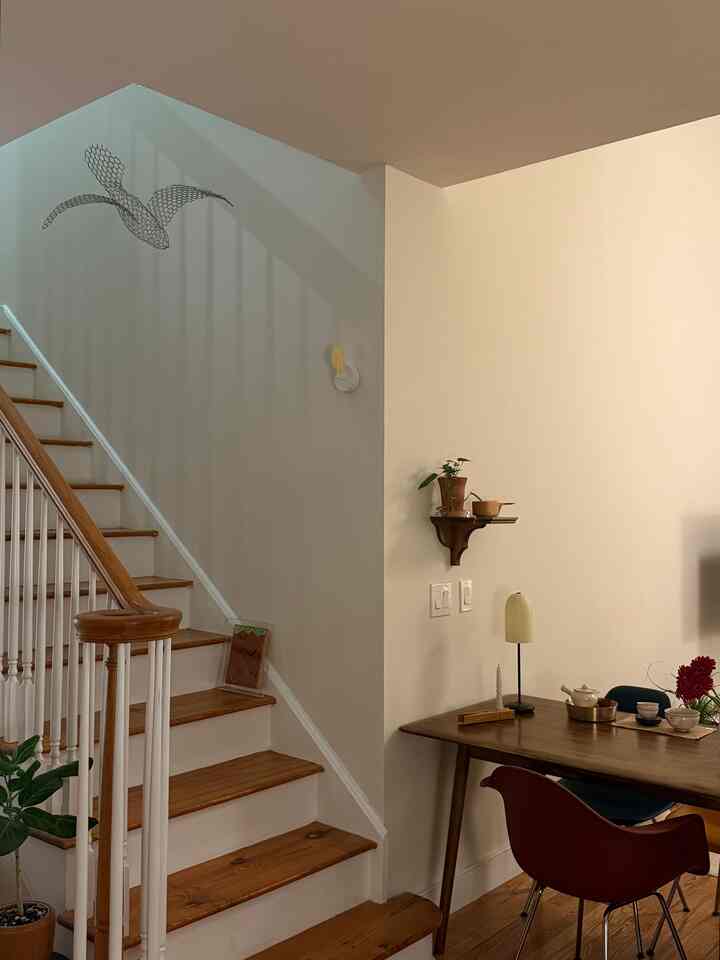 Cozy living space featuring warm natural color tones with wooden stairs and dining table