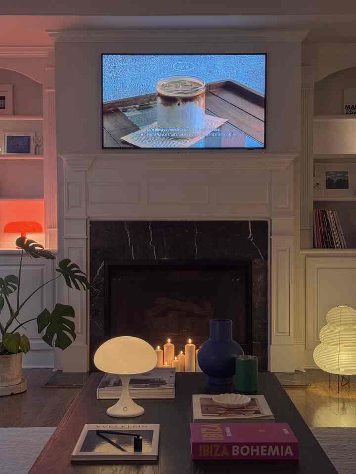 Cozy living room with warm lighting and candles, featuring a central fireplace and mounted TV