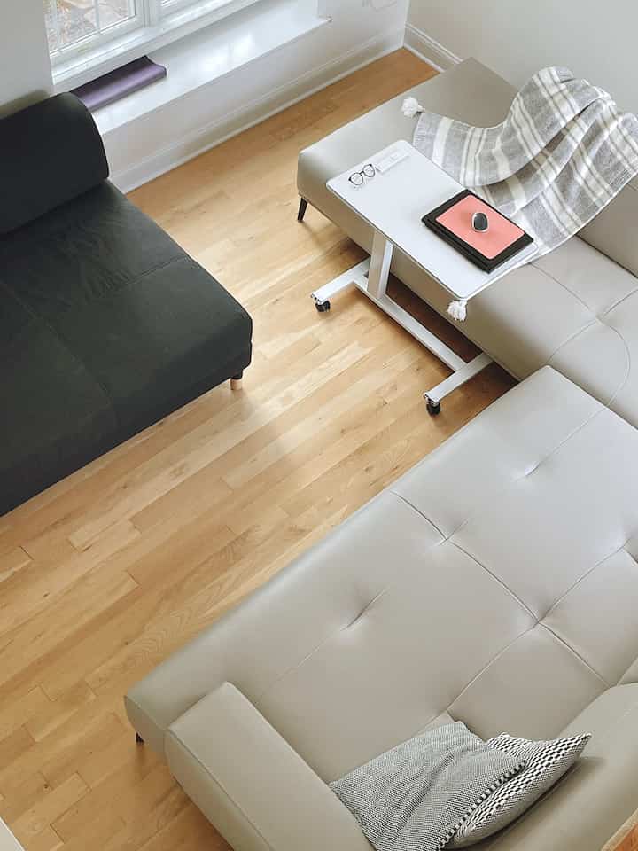 Light brown wooden floor and gray-toned sectional sofa in a simple and minimal living room space