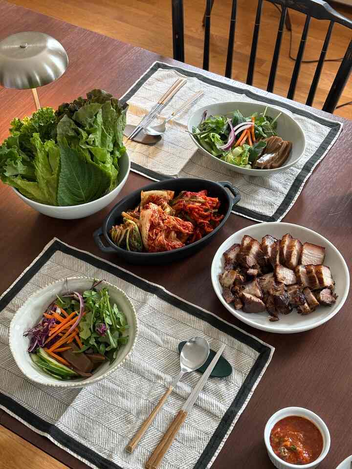 Natural tone wood dining room featuring a wooden table with Korean dishes and bowls in a cozy setting
