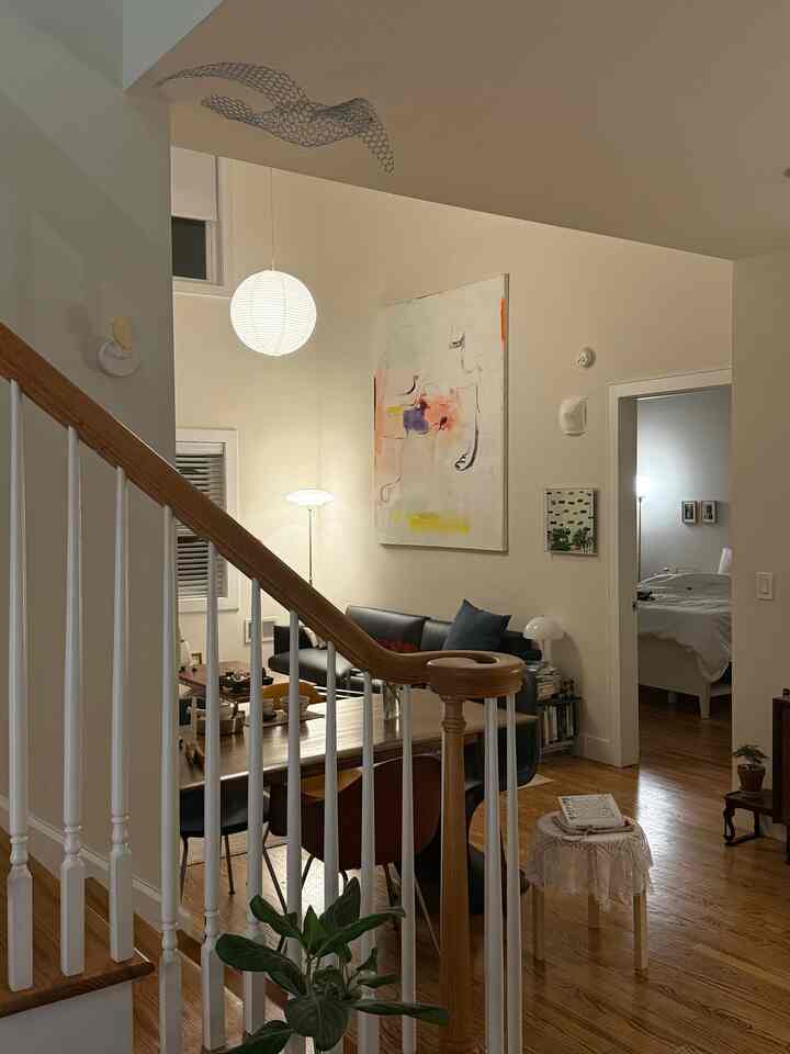 White and brown toned living and dining room featuring black sofa and large dining table in a cozy interior