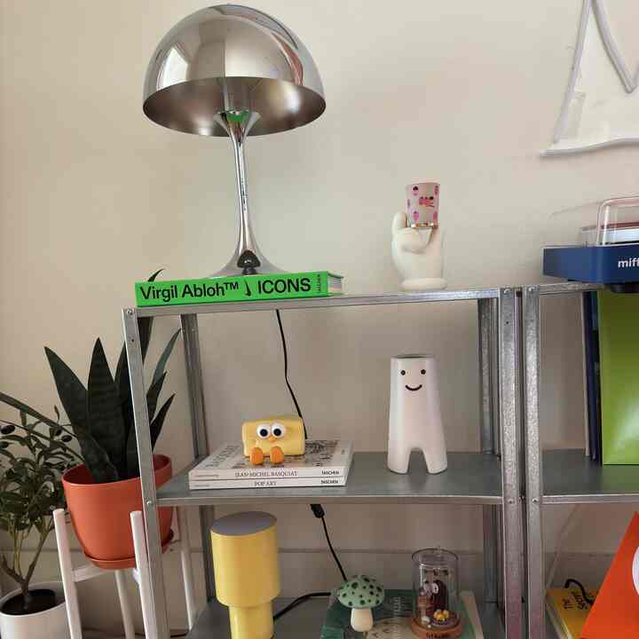 Natural color wall with metal shelves displaying colorful objets in a simple modern interior space