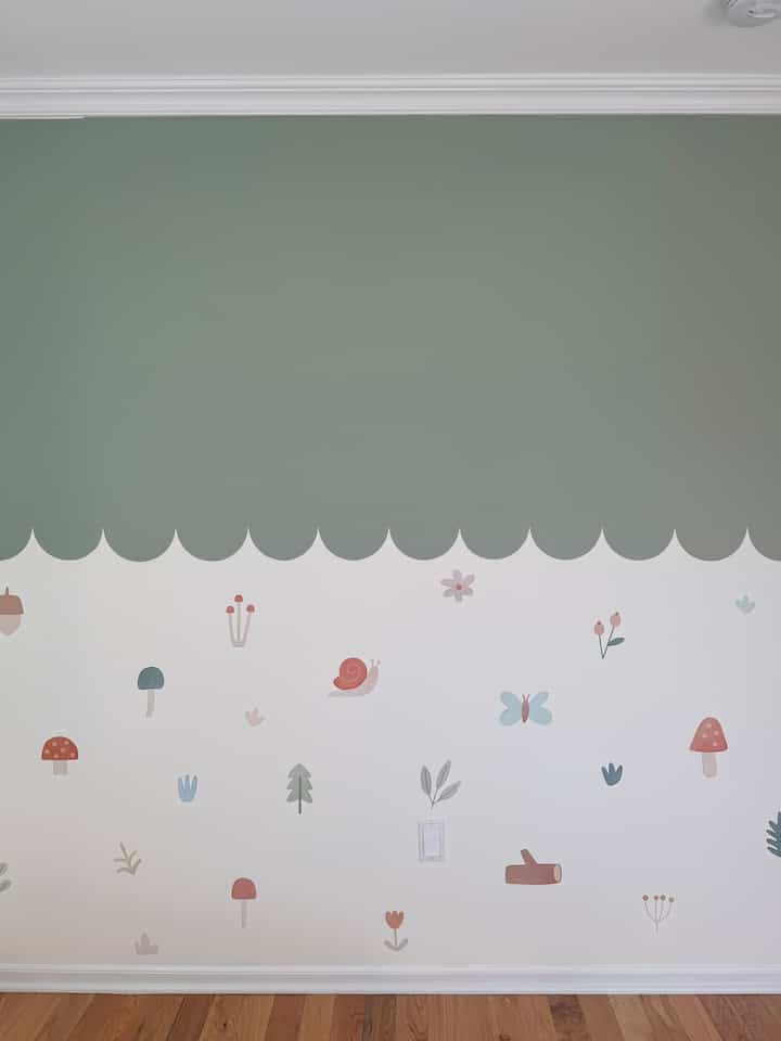A light green and white-toned wall decorated with woodland mushroom and butterfly wall decals in a charming kid's room.
