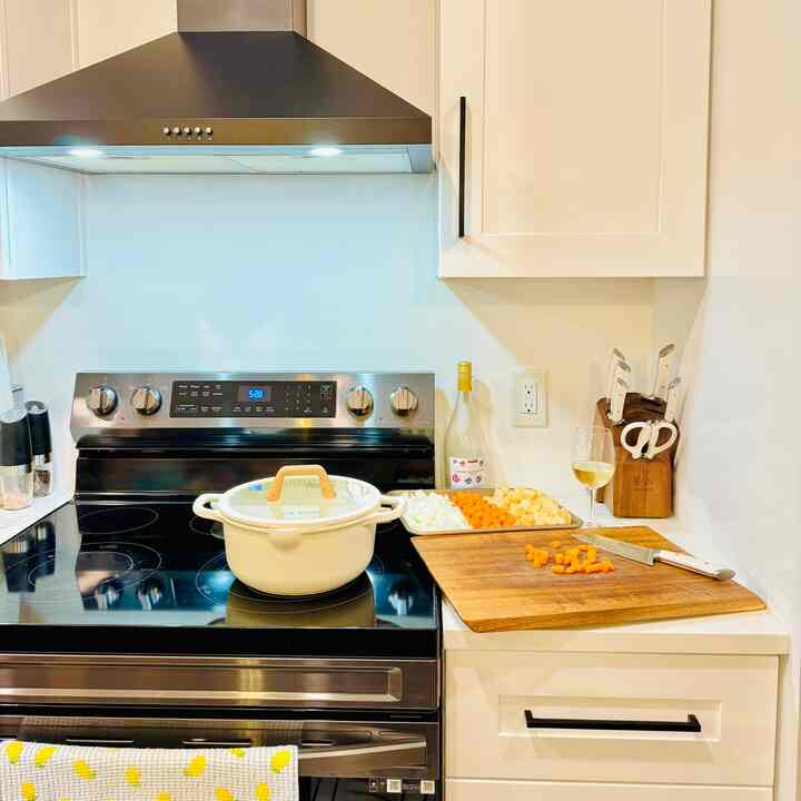 White and black toned kitchen featuring acacia cutting board and cooking tools with a warm, cozy atmosphere