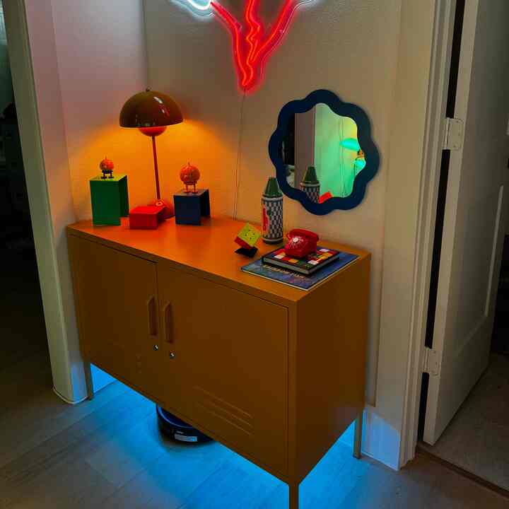 Retro-style space featuring an orange cabinet with blue framed mirror and colorful decorative objects
