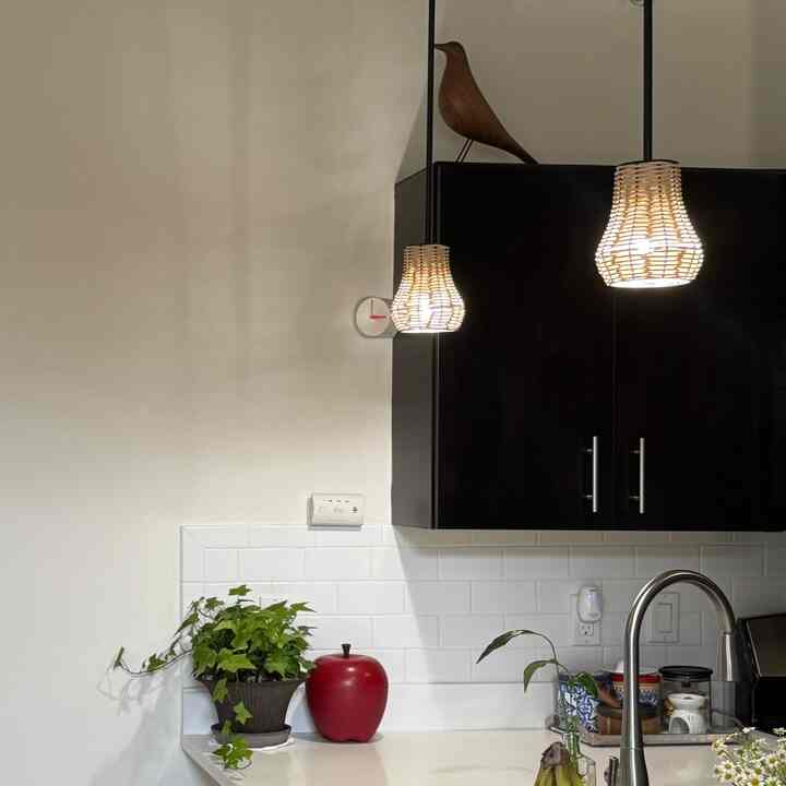 Modern kitchen space with white walls, black upper cabinets, and rattan pendant lights