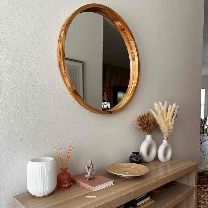 Cozy living room with natural wood-toned console table featuring diffuser, vases, and decorative sculptures