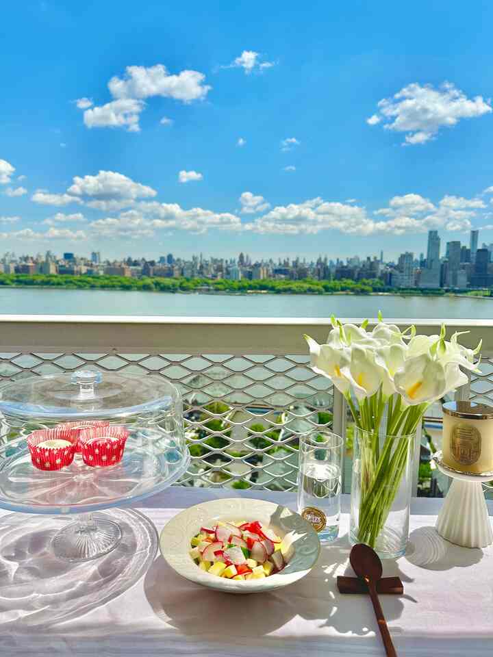 Bright, transparent white-toned balcony featuring a table with vase, drinks, and desserts creating a romantic atmosphere