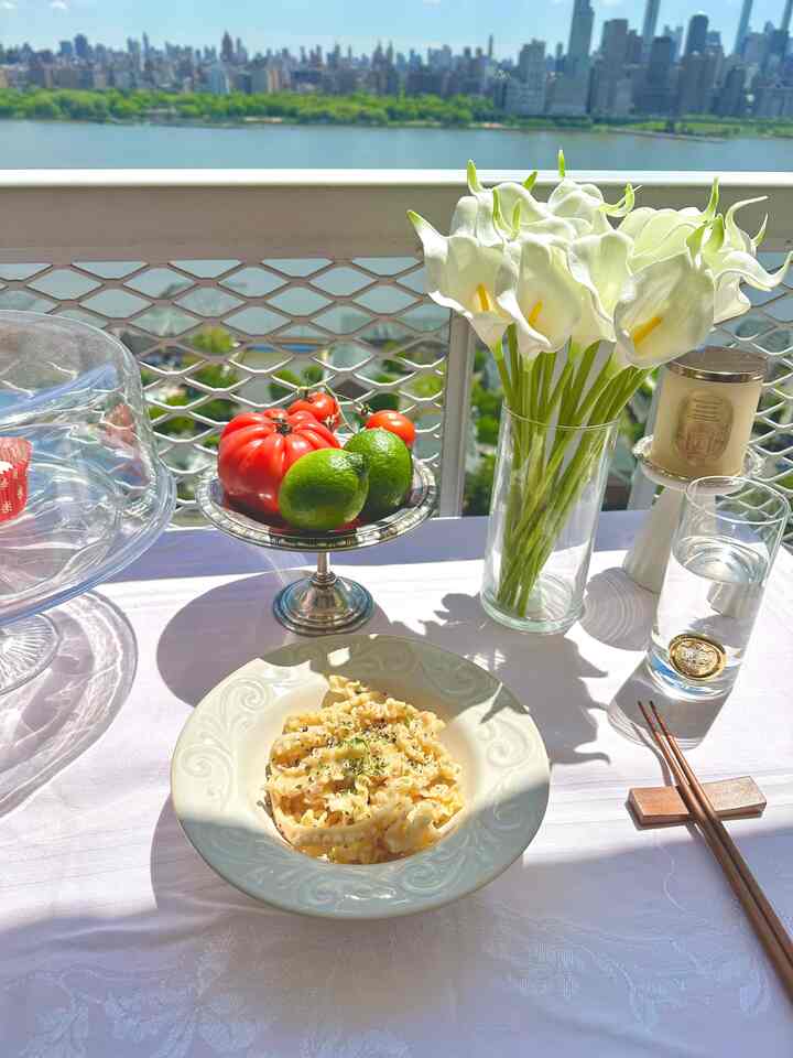 Bright white tablecloth on a balcony setting featuring a clear glass vase with white artificial calla lilies, overlooking a city and river view for a cozy dining atmosphere