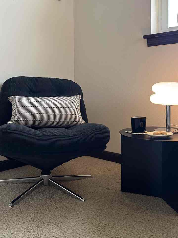 Cozy corner space with a black armchair and white table lamp