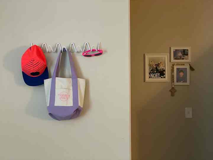 A simple entrance space in white and beige tones featuring a coat rack and picture frames