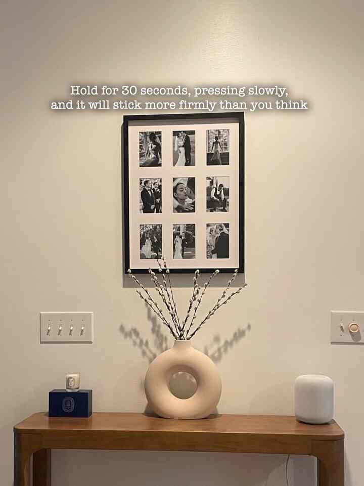 Beige and wood tone entrance featuring a round ceramic vase and framed black-and-white photos in a minimal style