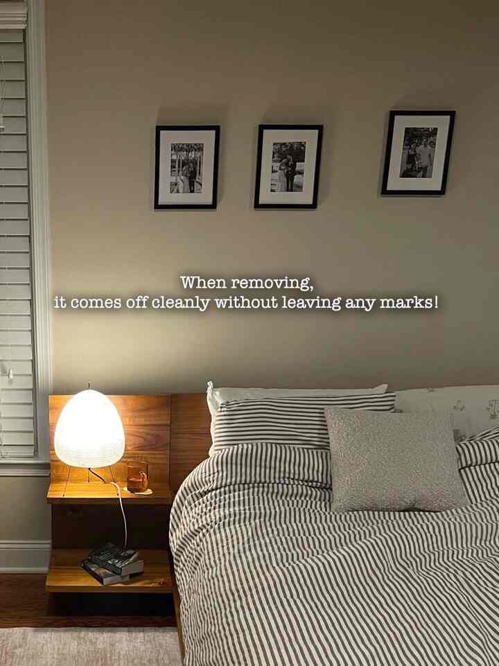Beige-toned bedroom featuring wood tone nightstand and Akari table lamp with striped bedding creating a cozy atmosphere