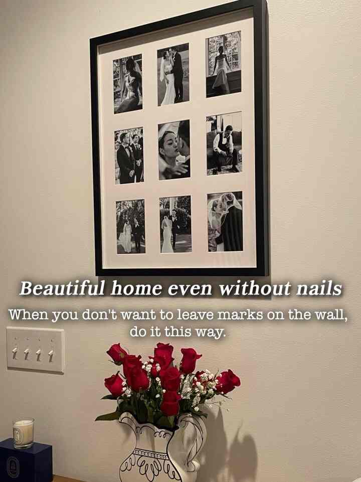 A simple space featuring white walls, a vase of red roses, and a black picture frame with black-and-white photos