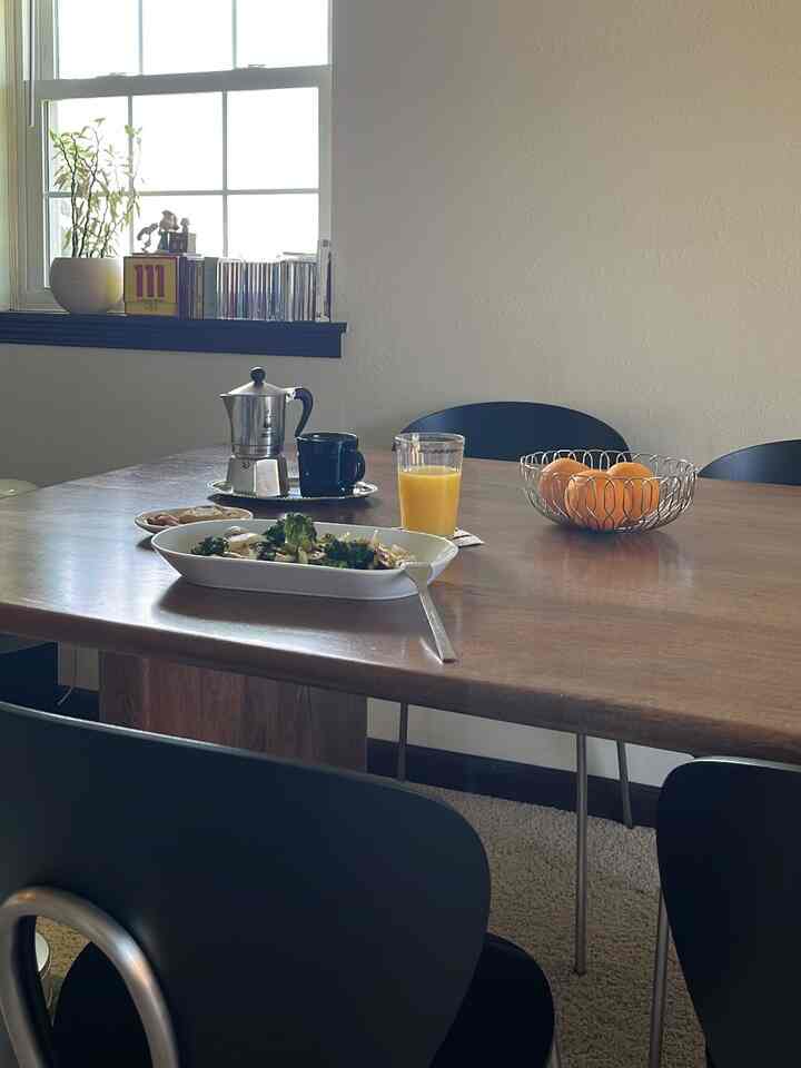 Modern dining room for four with white walls and wood-toned table, black chairs, and home cafe setup creating a cozy atmosphere