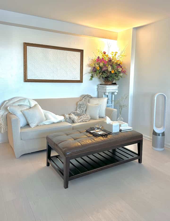 Ivory sofa and brown ottoman in a cozy French Country style living room space