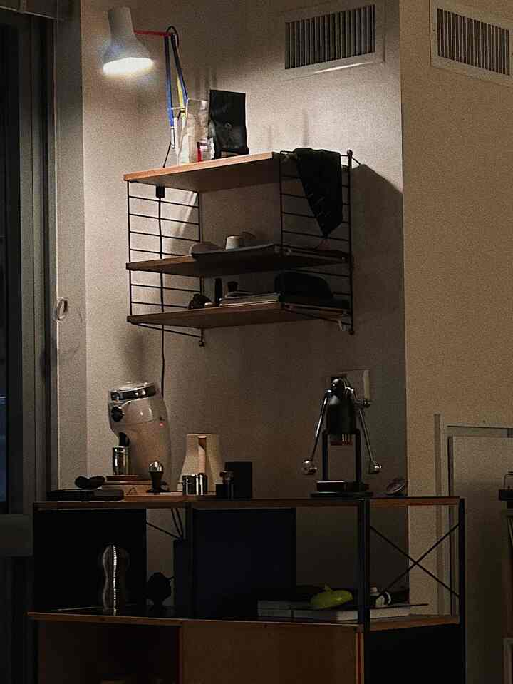 Warm brown-toned kitchen space featuring wall-mounted shelves and electric drip pot, showcasing a cozy home cafe setup