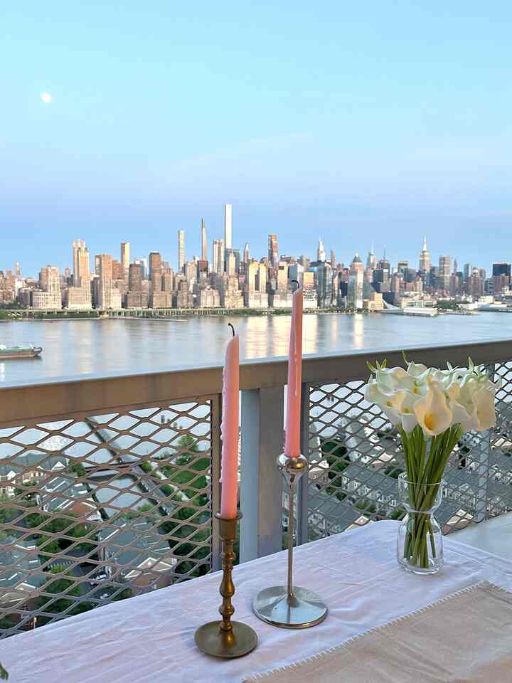 White and pink toned balcony featuring a simple, romantic setup with vase of flowers and candles on the table