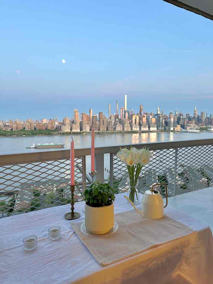 White and beige toned balcony with tablecloth, table runner, plants, and candles creating a romantic atmosphere