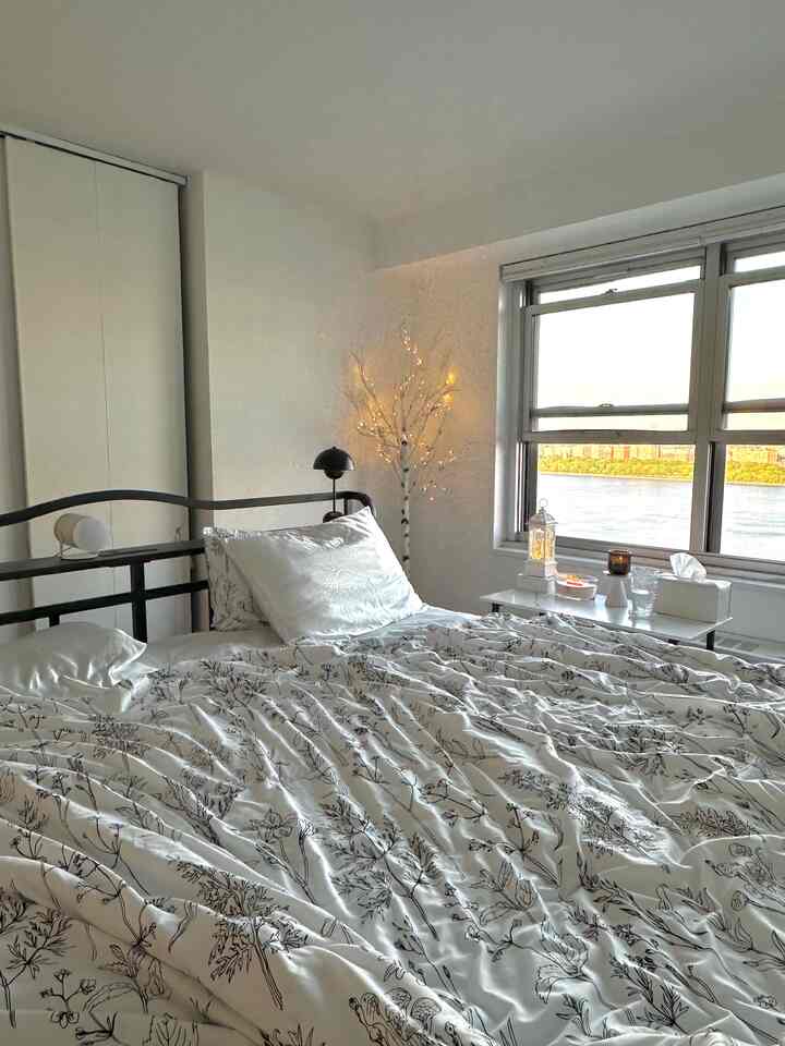White and natural toned bedroom featuring floral bedding and soft candlelight creating cozy ambiance