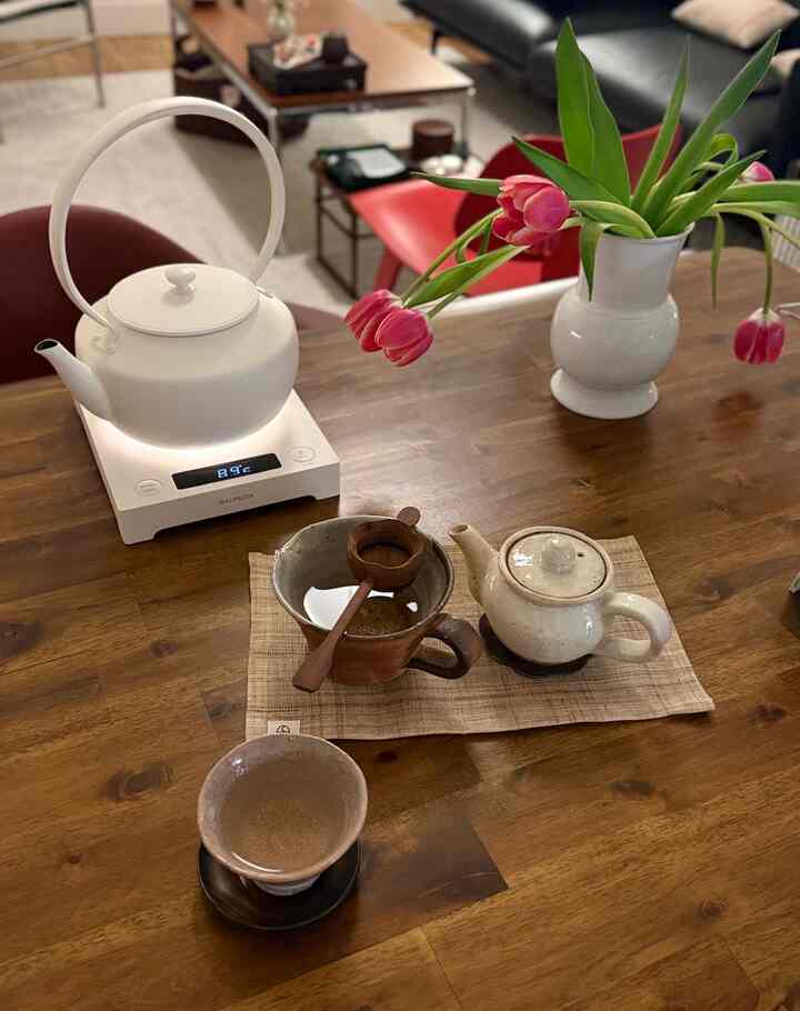 Cozy brown wooden table featuring a white MoonKettle, teacup, and vase creating a simple home cafe atmosphere