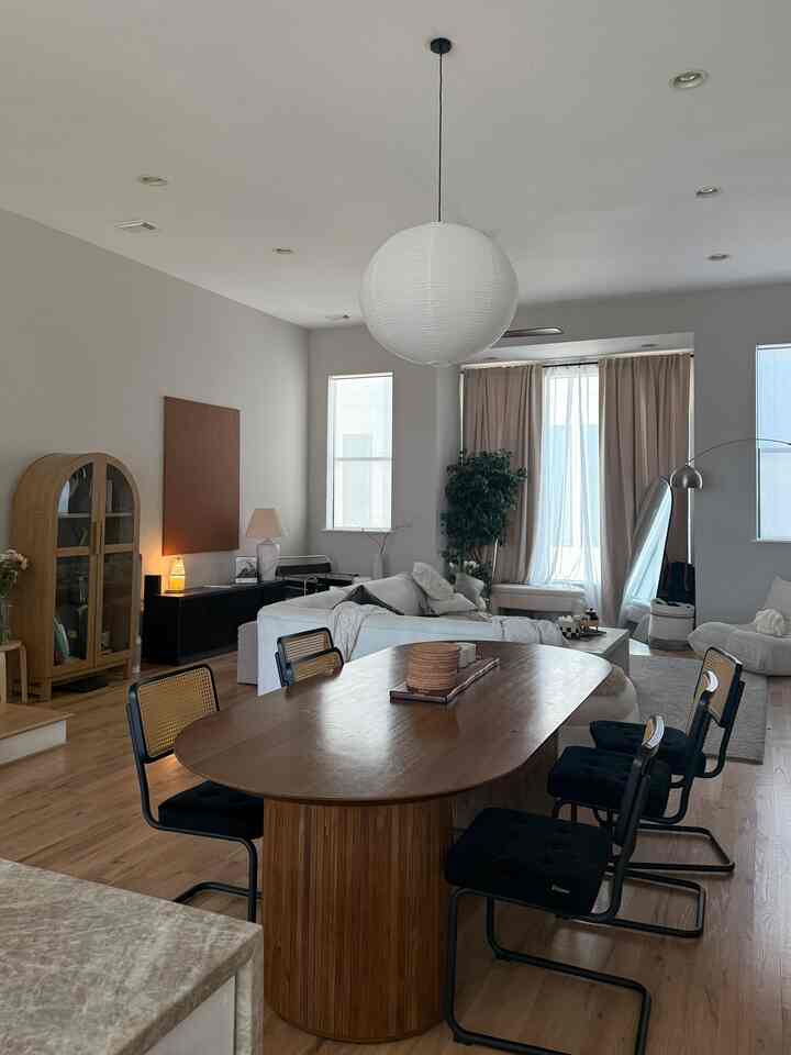 White and brown toned dining room and living room featuring a modern wooden dining table and white sofas in harmonious setting