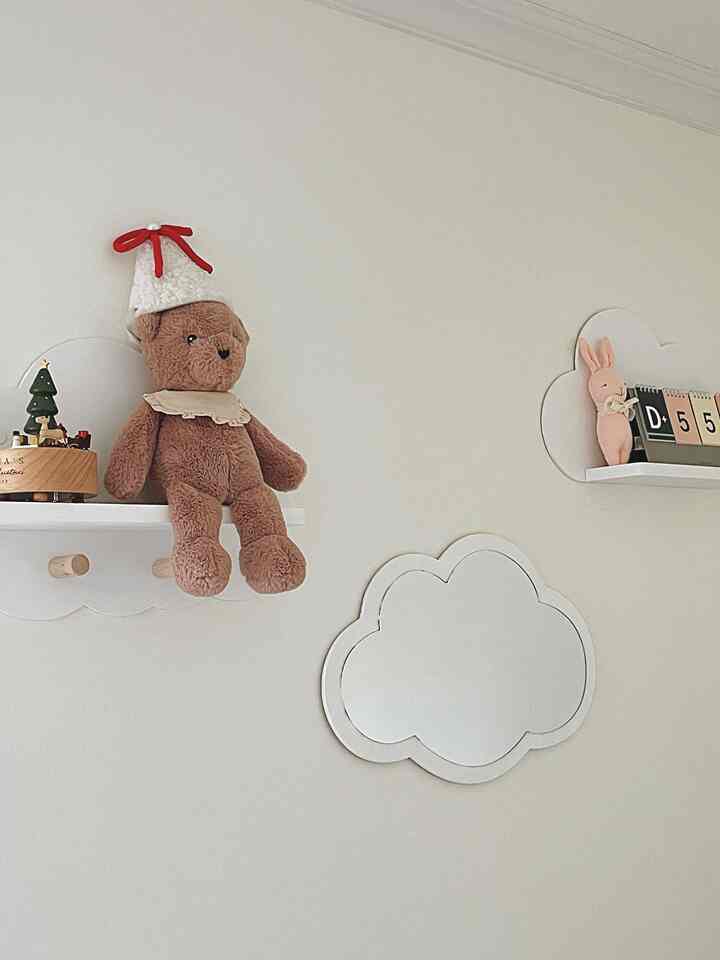 White-toned kids' room wall featuring cloud-shaped shelves and mirror, creating a neat and cute ambiance