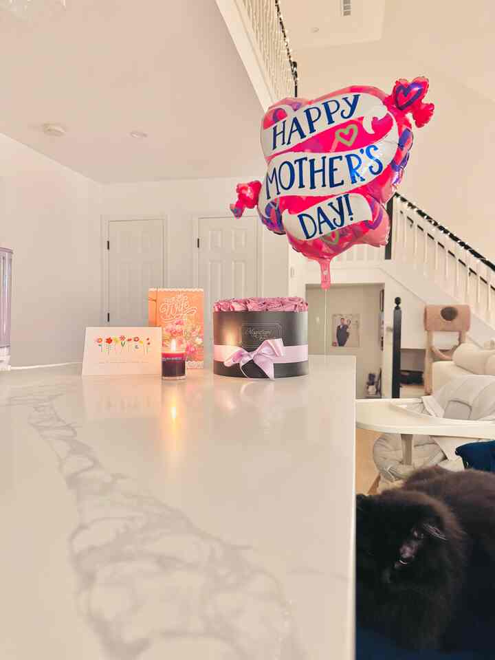 White-toned living room featuring a pink celebration balloon and floral decoration creating a clean, cozy atmosphere
