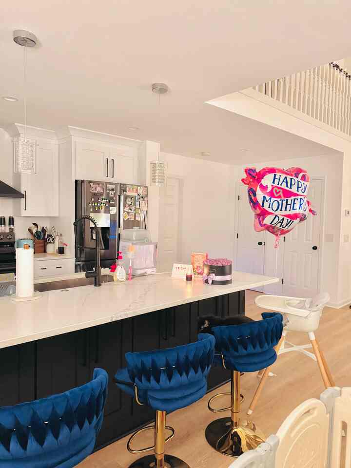 Bright kitchen in white and navy tones featuring navy bar stools and a baby high chair, clean and inviting atmosphere