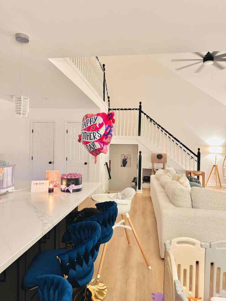 White and wood tone open kitchen and living room shared with baby and cat, creating a cozy family space
