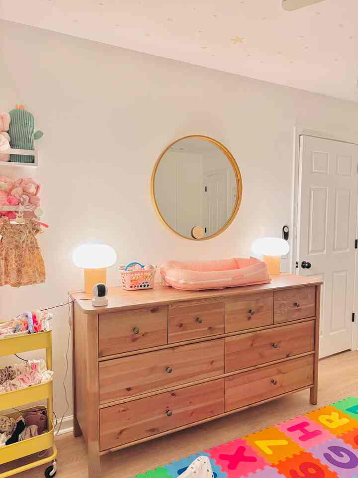 White and wood tone kids' room featuring table lamps and a large dresser with a cozy atmosphere