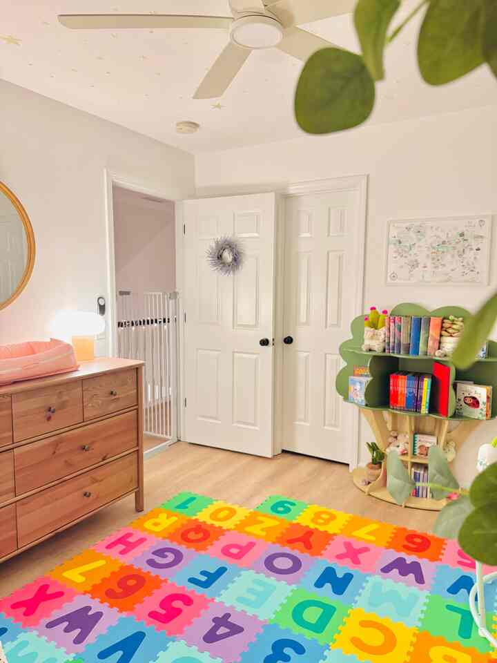 Bright white walls and ceiling with brown wooden dresser and colorful alphabet rug, cozy kids' room setup