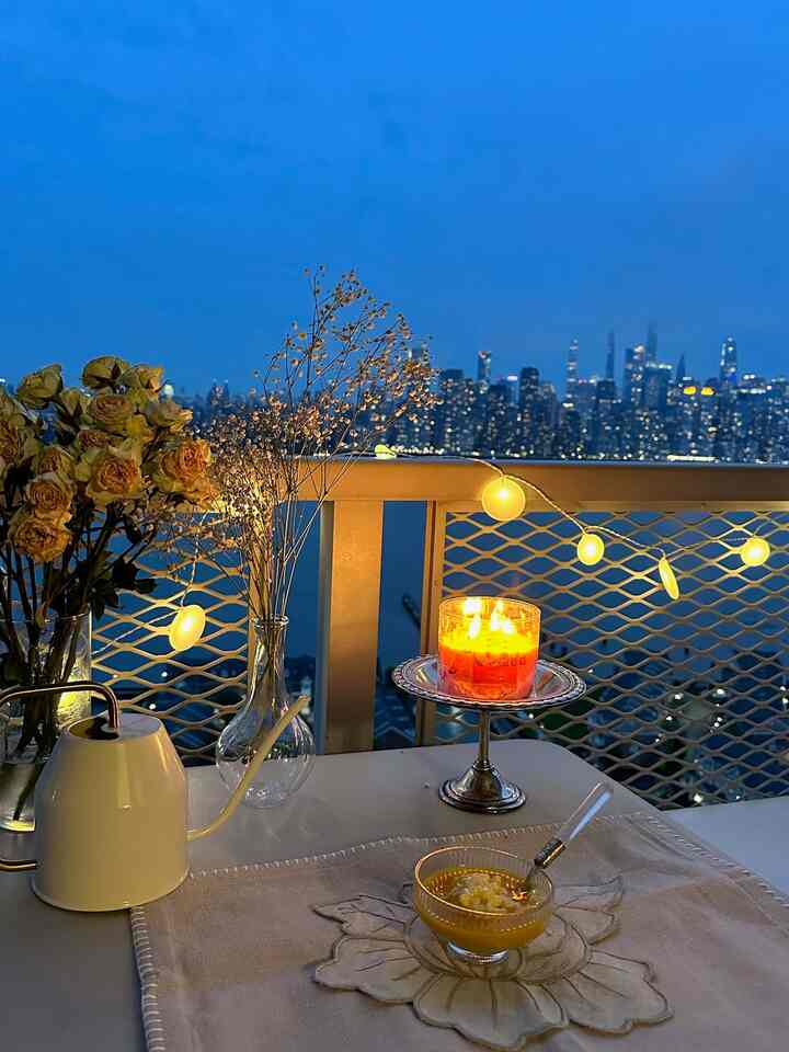 Clear blue-toned evening balcony featuring vases, a lit candle, and home cafe accessories with a romantic ambiance