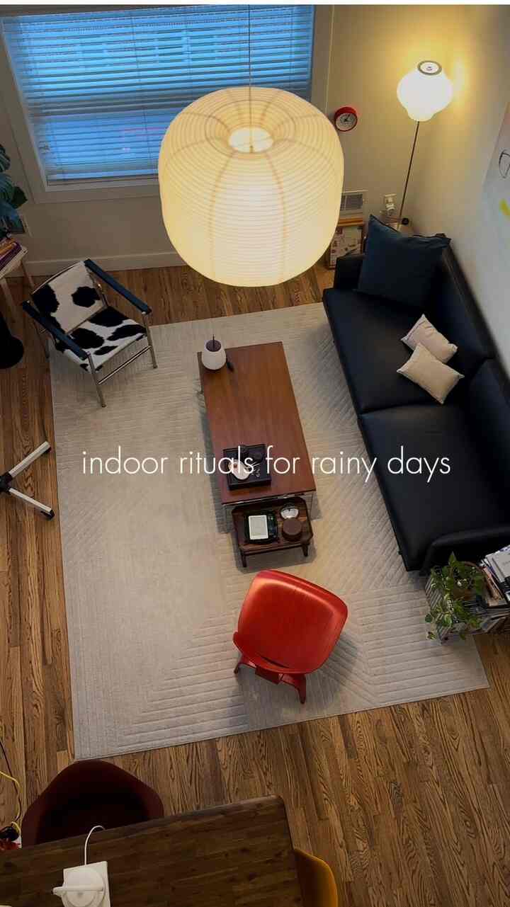 Natural color toned living room featuring a black sofa and red armchair with cozy atmosphere