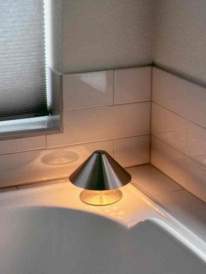 White and beige-toned bathroom featuring a metallic table lamp in the corner creating a cozy atmosphere