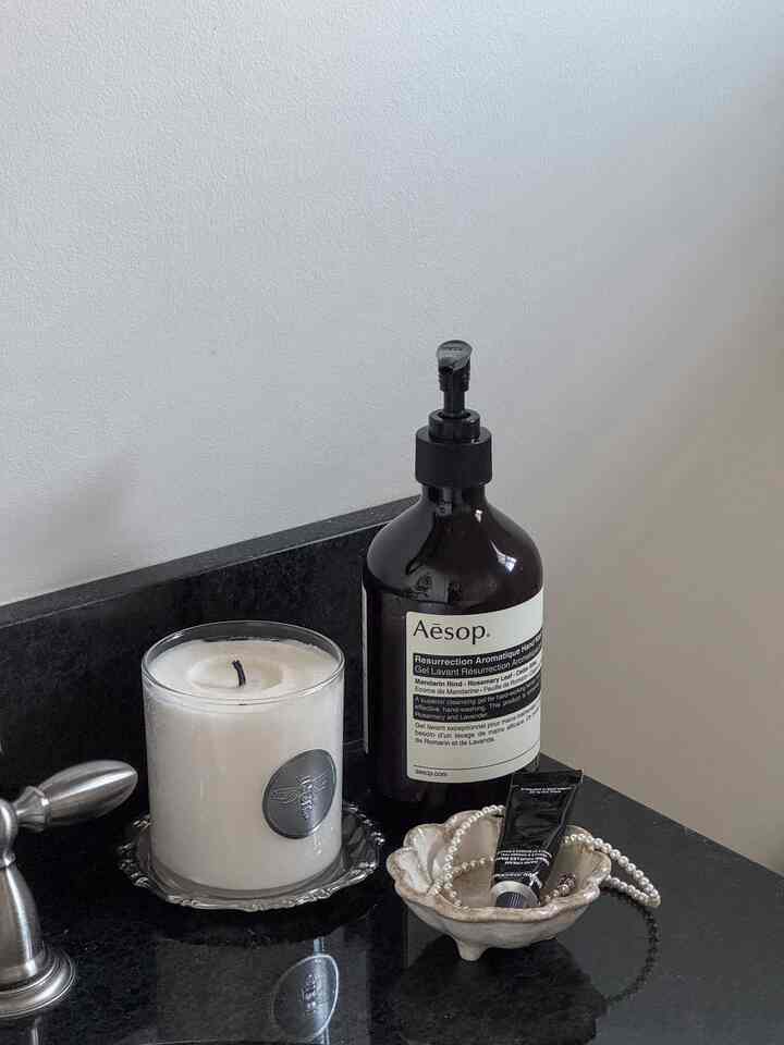 Bathroom space with white candle and black Aesop hand wash placed on black marble countertop