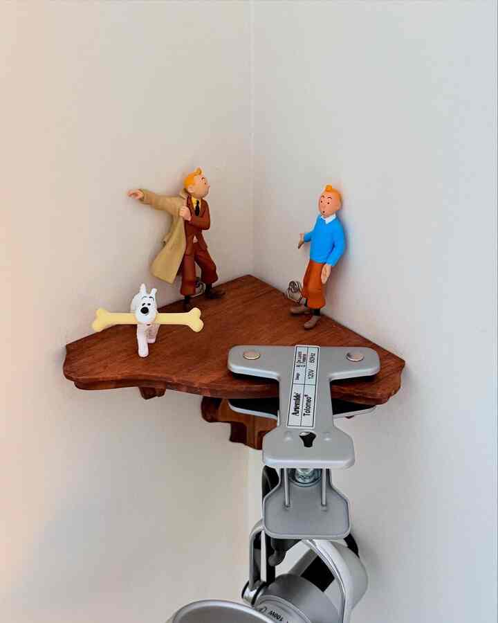 White walls with a wood tone corner shelf displaying decorative objets creating a clean corner space