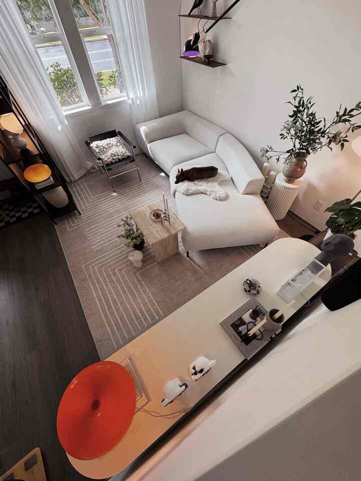 A white and beige toned living room featuring a modern sofa and armchair, creating a cozy and clean ambiance