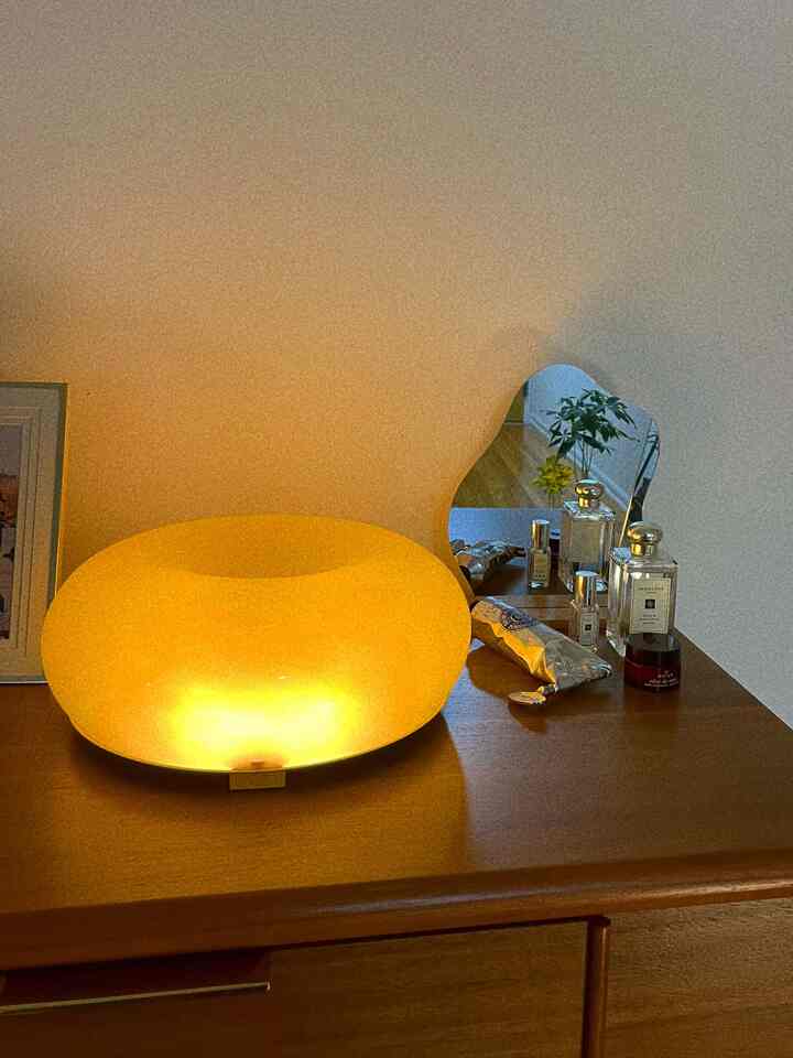 Natural color bedroom dresser space featuring a gold-tone LED table lamp and an irregular-shaped mirror