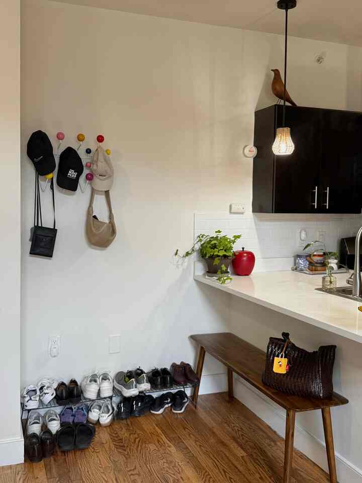 Natural wood tones and white walls in an entrance area featuring a bench and organized shoe storage, creating a cozy atmosphere