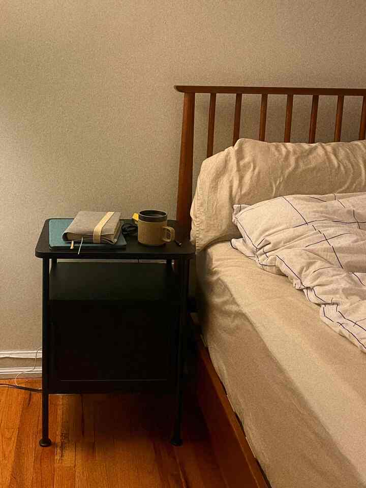 Natural bedroom with brown wooden bed and black nightstand, simple and cozy atmosphere