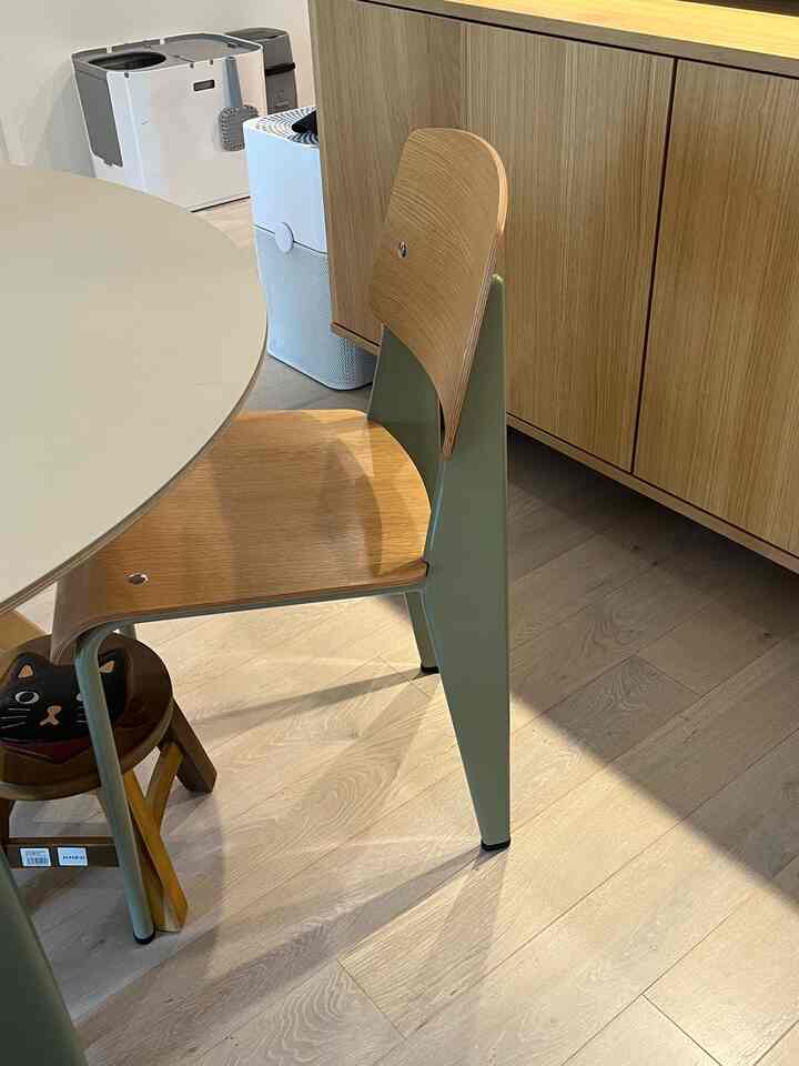 Natural dining space featuring wood tone dining chair and storage cabinet with beige round table surface