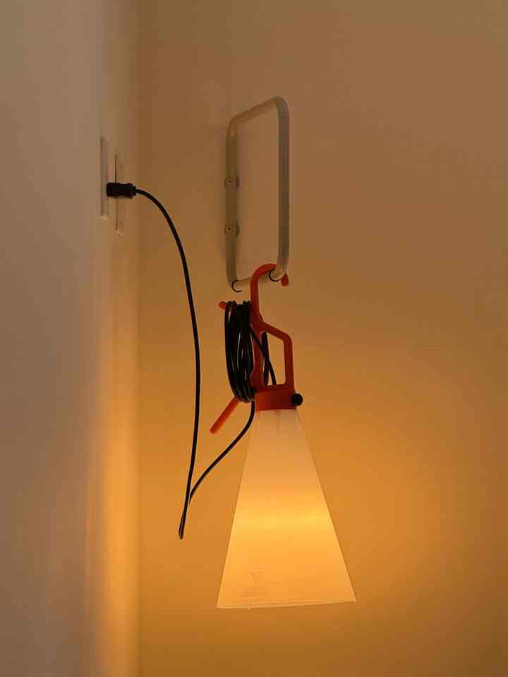 A simple, modern space featuring a wall-mounted floor lamp with an orange handle against warm beige walls