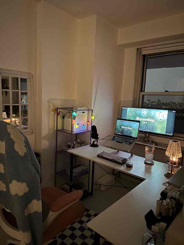 White-toned home office space featuring desk, monitor, and microphone in a cozy remote work setup