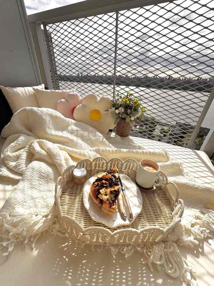 Bright white and natural-toned balcony daybed featuring cushions and a brunch setup creating a cozy outdoor space