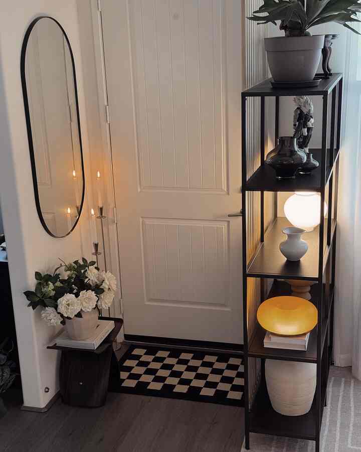 White and black toned entrance featuring black shelves, white vase with flowers, candles, and lamps creating a modern cozy ambiance