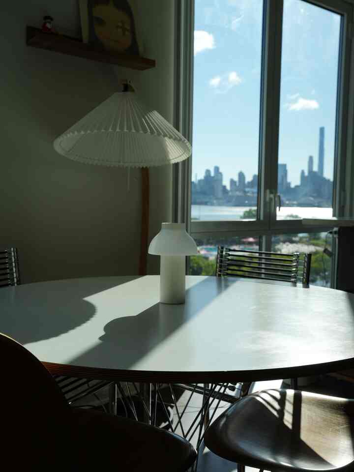 White-toned dining room featuring modern round dining table and chairs with cityscape view