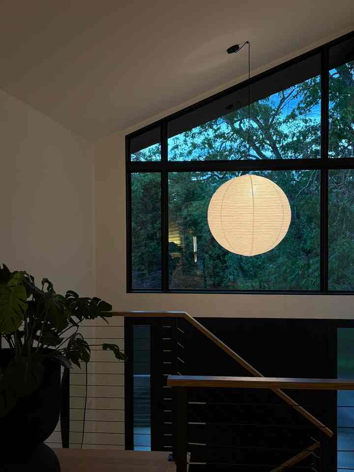 Natural-toned entrance space featuring a large window, spherical pendant light, and a lush plant creating a cozy atmosphere