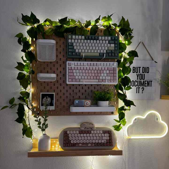 Modern home office with white walls and wood-tone shelving, featuring keyboards, plants, and decorative lighting in a cozy workspace